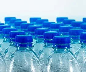 Arranged plastic water bottles with blue caps, highlighting freshness and hydration for consumers.