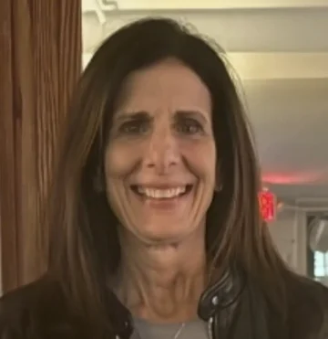 Stylish woman smiling in a cafe with cozy ambiance and warm lighting.